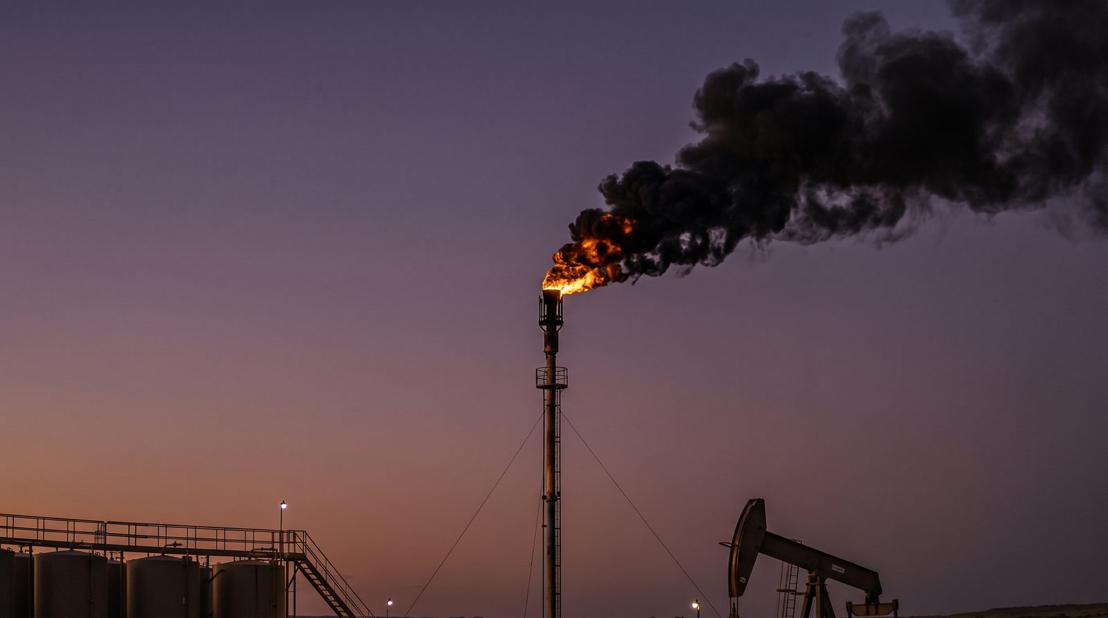 Camera view of a flare tip trailing black smoke at dusk